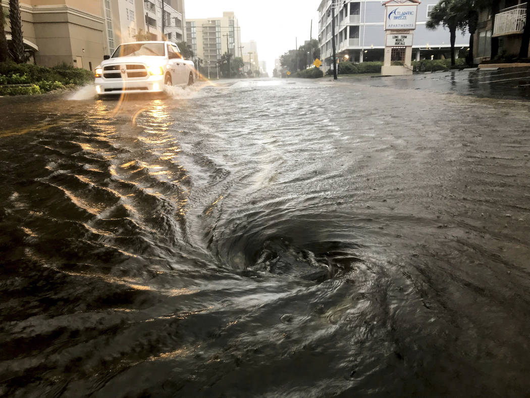 Floodwaters swirl around a storm drain as heavy rain falls from Hurricane Dorian, Thursday, Sep ...