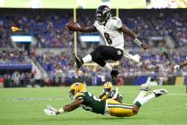 Baltimore Ravens quarterback Lamar Jackson (8) leaps over Green Bay Packers cornerback Jaire Al ...