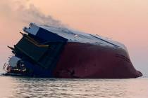 Coast Guard crews and port partners respond to an overturned cargo vessel with a fire on board ...