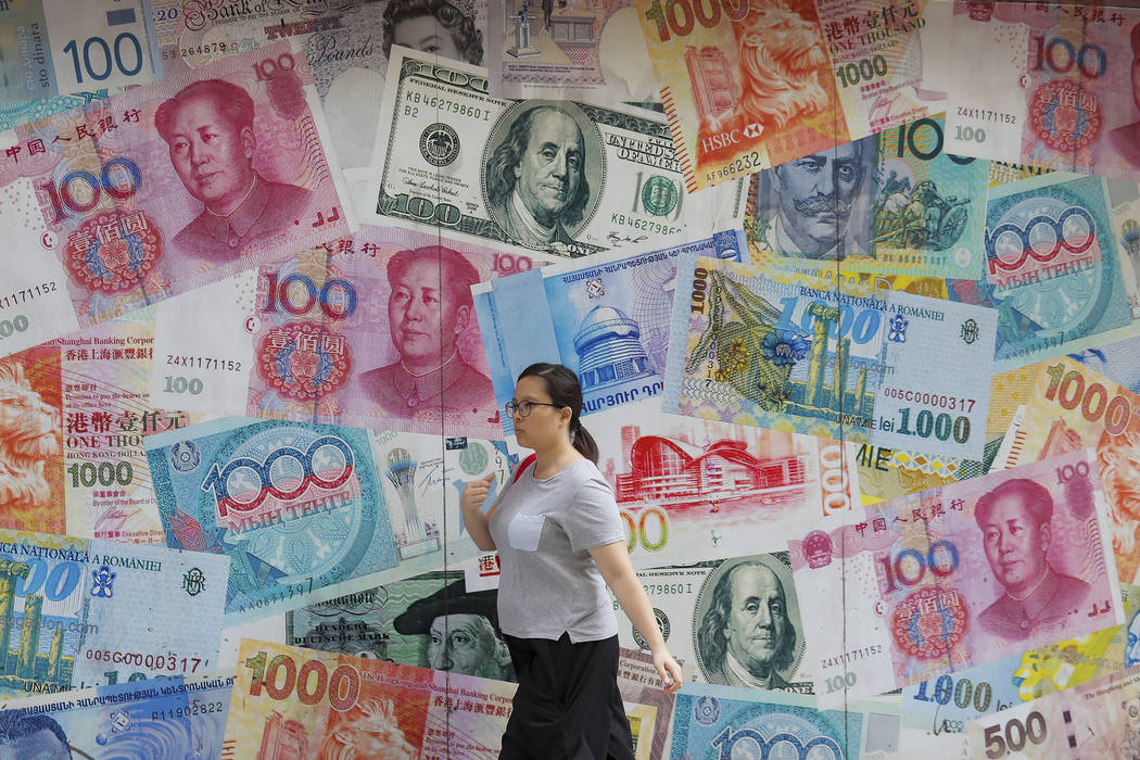 FILE - In this Aug. 6, 2019, file photo, a woman walks by a money exchange shop decorated with ...