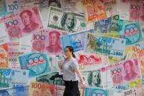 FILE - In this Aug. 6, 2019, file photo, a woman walks by a money exchange shop decorated with ...