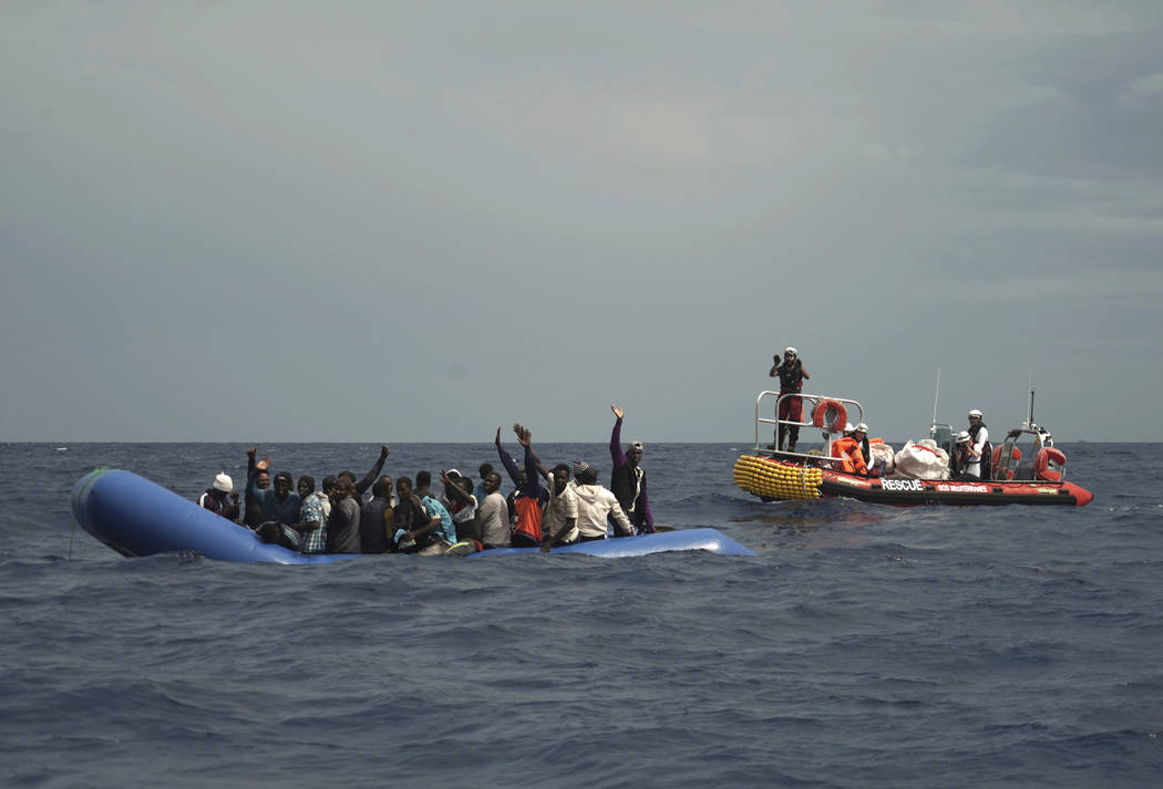 Migrants are seen waving after being found some 14 nautical miles from the coast of Libya in Me ...