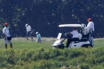 President Donald Trump, right, drives a golf cart during a round of golf at the Trump National ...