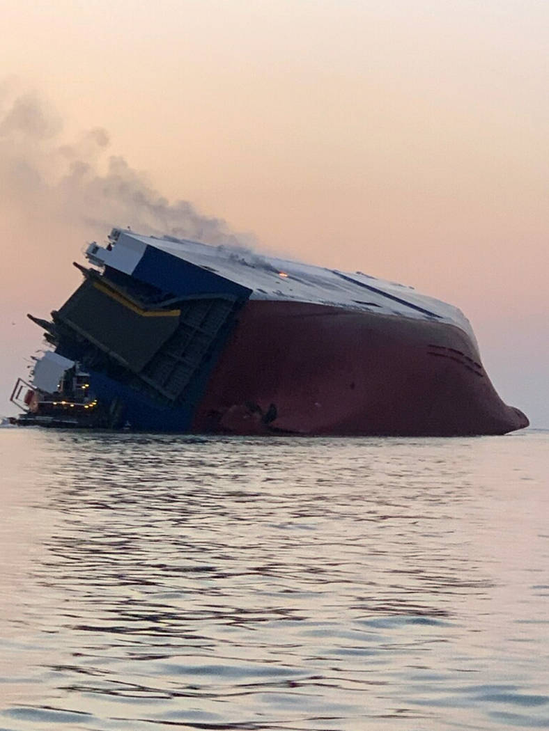 Coast Guard crews and port partners respond to an overturned cargo vessel with a fire on board ...