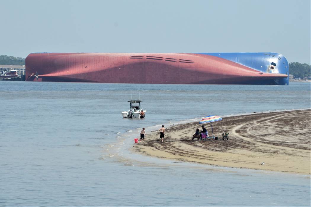 People are shown on Jekyll Island's Driftwood Beach as the Golden Ray cargo ship is capsized in ...