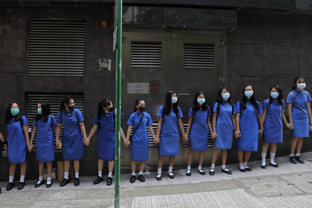 Students wearing mask hold hands to surround St. Stephen's Girls' College in Hong Kong, Monday, ...