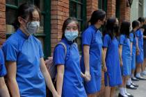 Students wearing mask hold hands to surround St. Stephen's Girls' College in Hong Kong, Monday, ...
