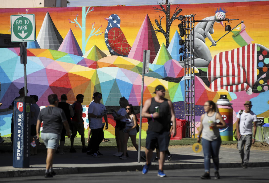 Attendees pass by a new mural during the first day of the Life is Beautiful festival in downtow ...