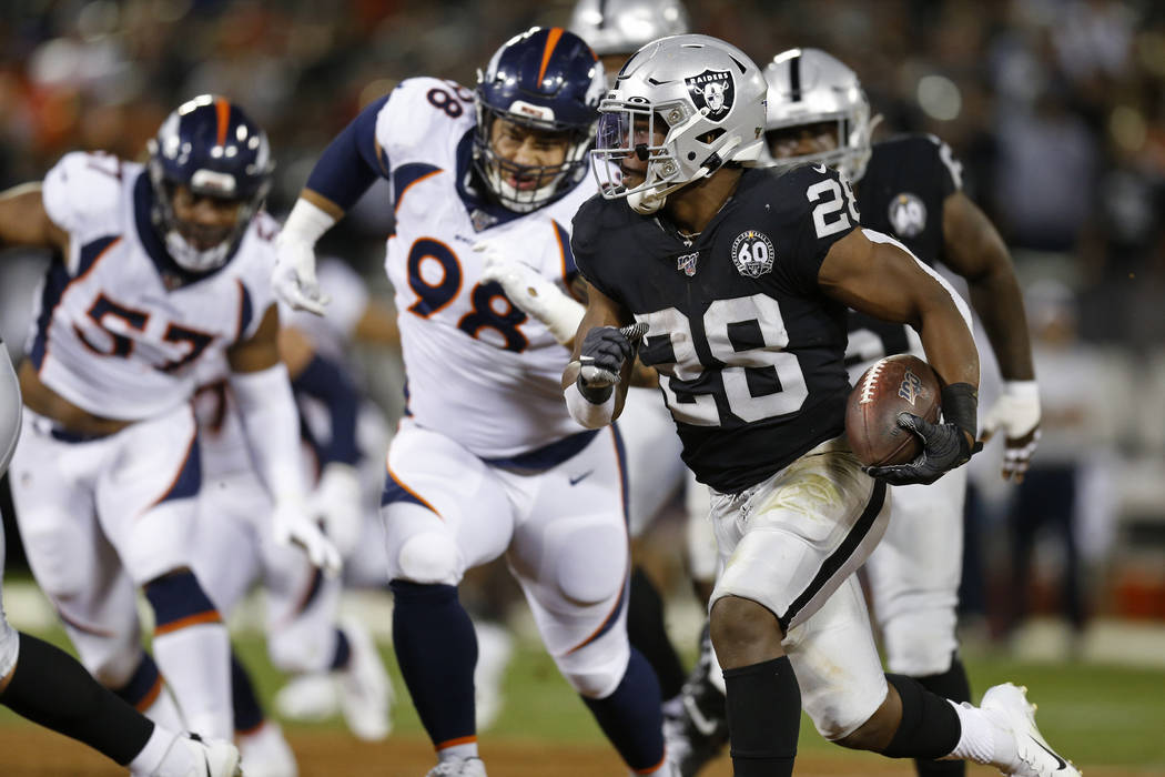 Oakland Raiders running back Josh Jacobs runs with the ball as Denver Broncos defensive end DeM ...