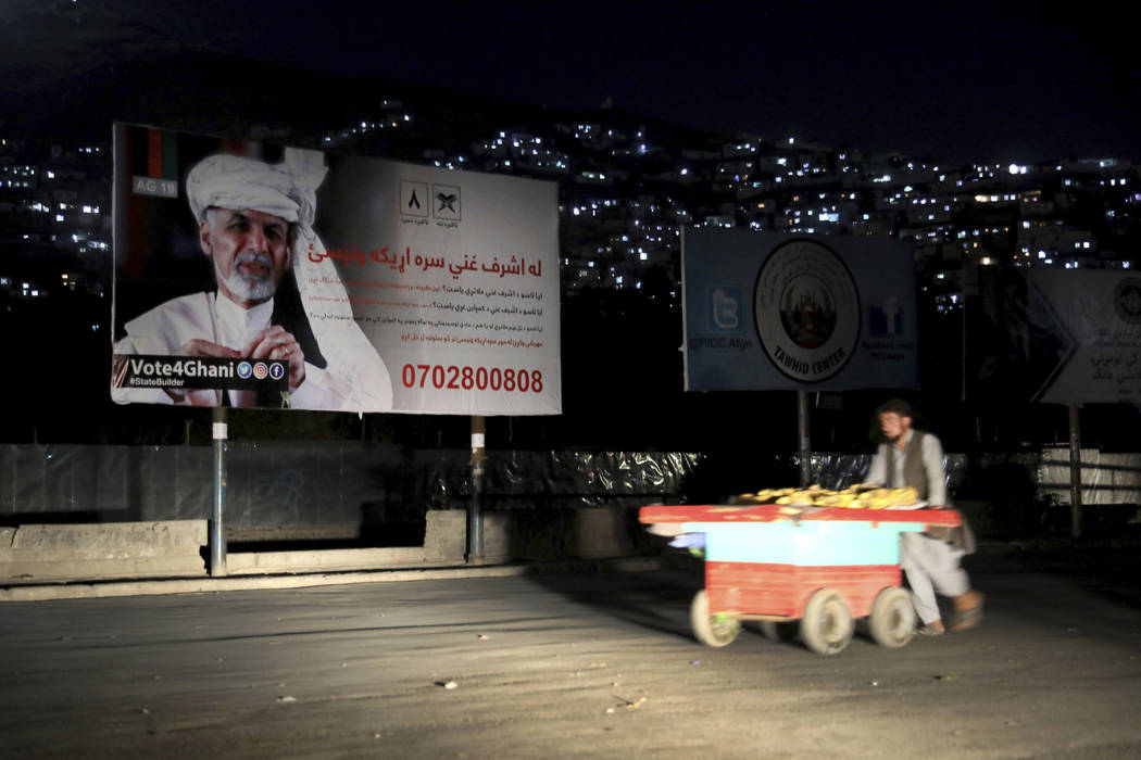 In this Sept. 9, 2019, photo, an Afghan street vendor pulls his hand cart in front of an electi ...