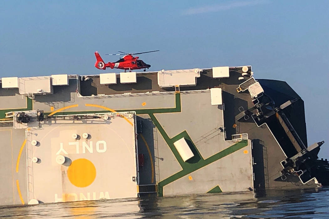 In this image released by the U.S. Coast Guard, a USCG helicopter hovers over an overturned car ...