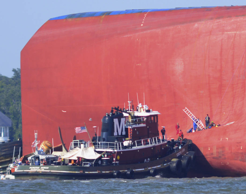 A member of a rescue party places a ladder in a hole cut in the hull of the cargo ship Golden R ...