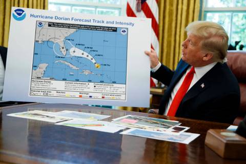 President Donald Trump holds a chart as he talks with reporters after receiving a briefing on H ...