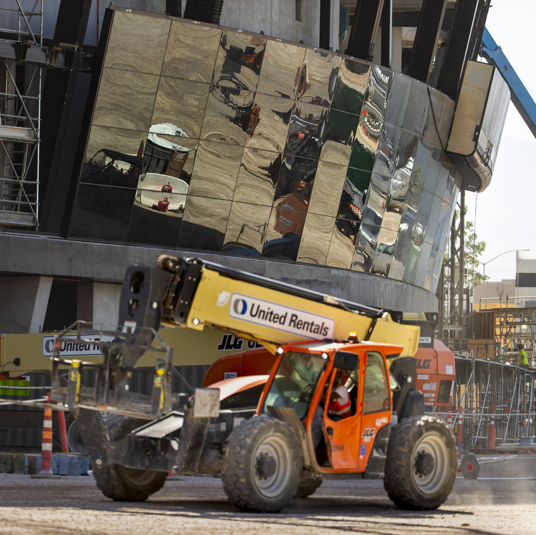 Crews work to install glass panes along the lower lever of Allegiant Stadium on Tuesday, Sept. ...