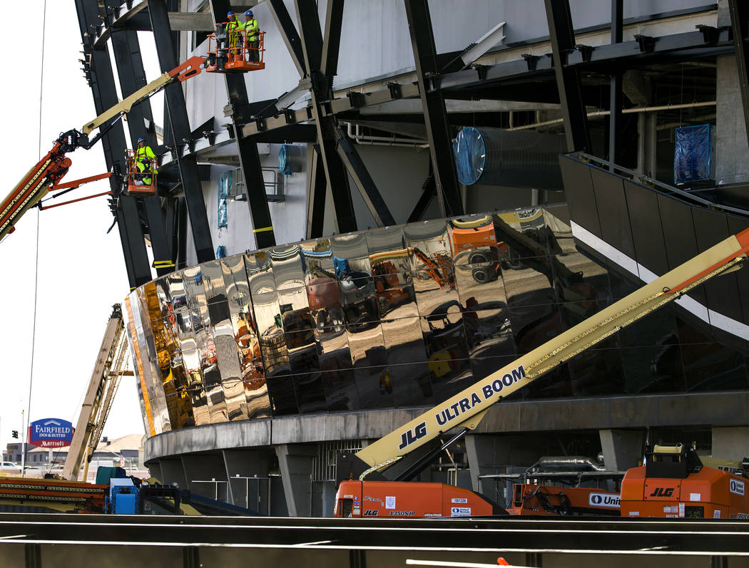 Crews work to install glass panes along the lower lever of Allegiant Stadium on Tuesday, Sept. ...