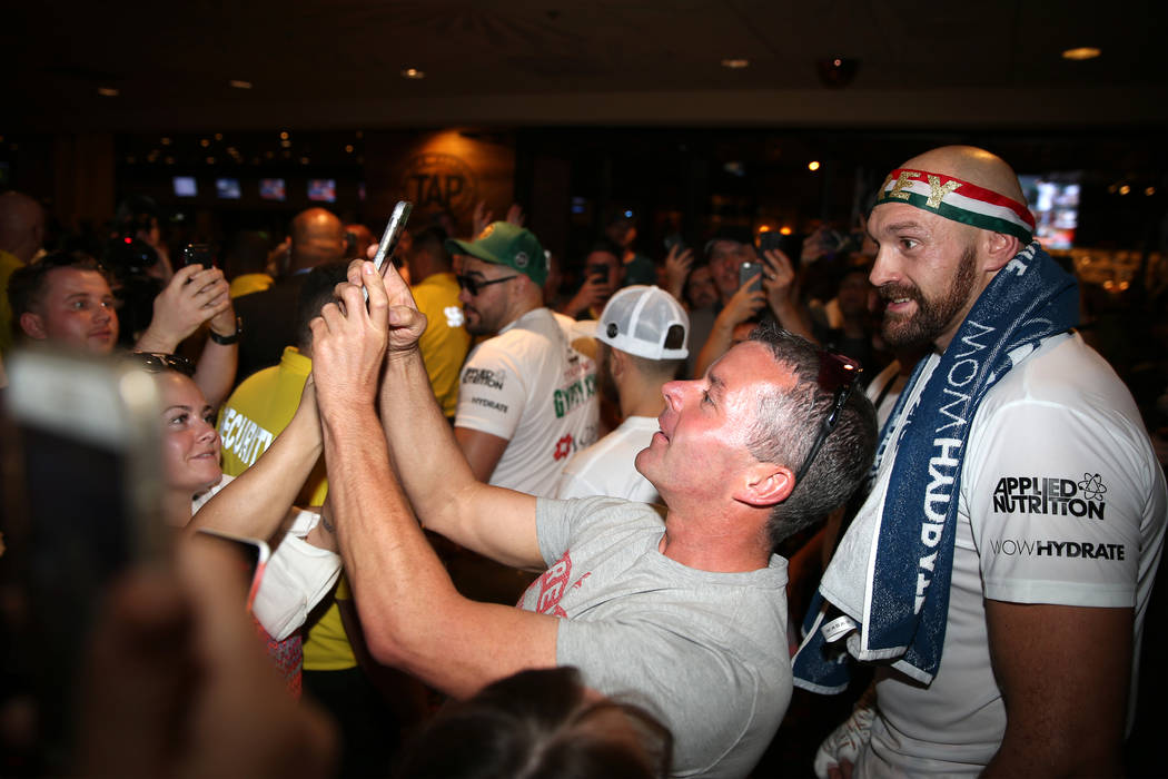 Heavyweight fighter Tyson Fury, right, takes a photo with fans following his open workout at th ...