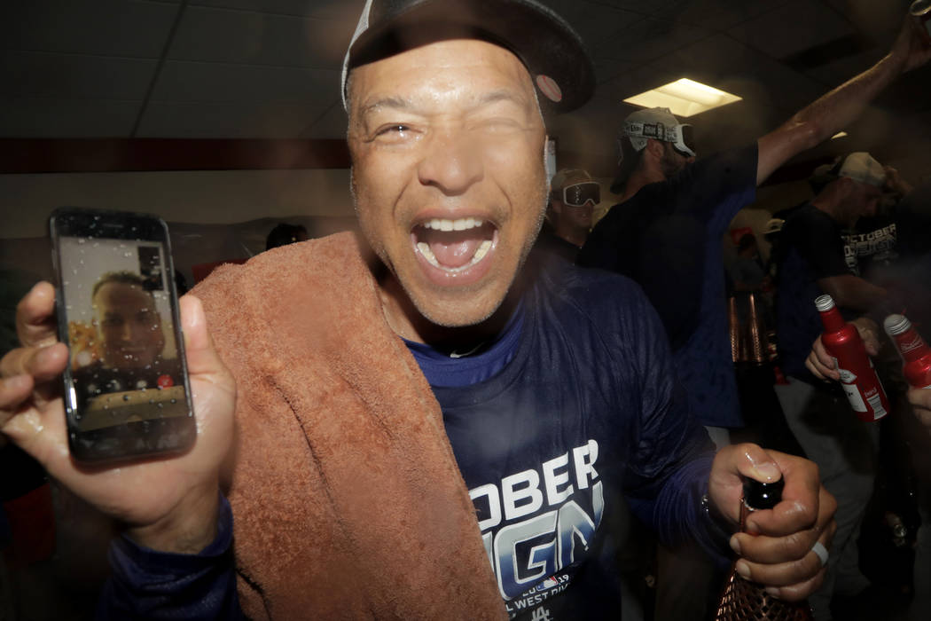 Los Angeles Dodgers manager Dave Roberts holds a cell phone during a video conference with inju ...