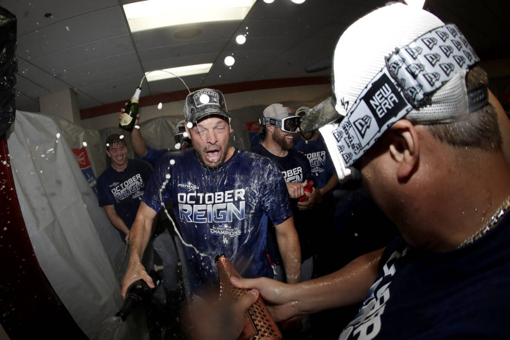 Los Angeles Dodgers pitcher Rich Hill, center, is doused during a lockerroom celebration after ...