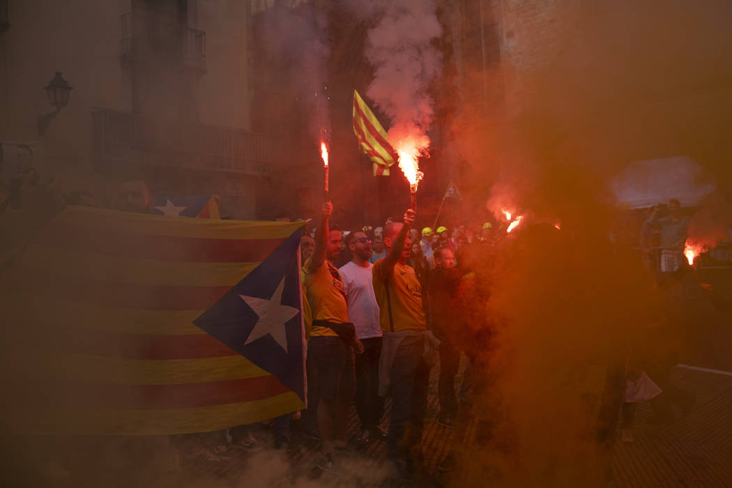 Protesters hold independence flags and flares during the Catalan National Day in Barcelona, Spa ...