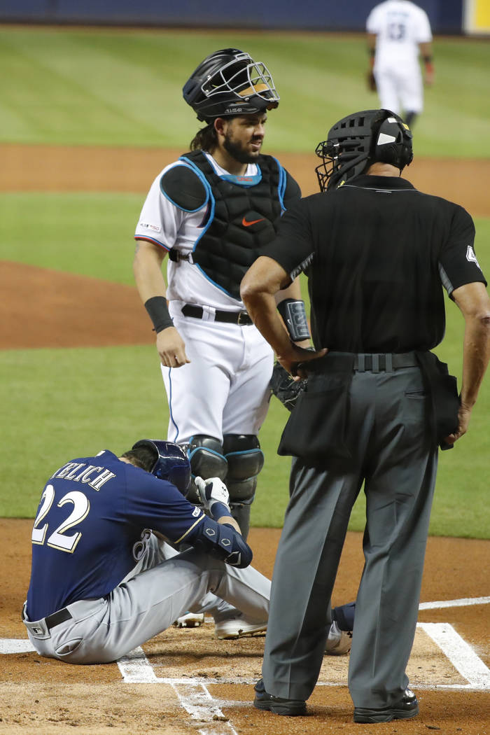 Milwaukee Brewers' Christian Yelich (22) sits on the ground after an injury while at bat as Mia ...
