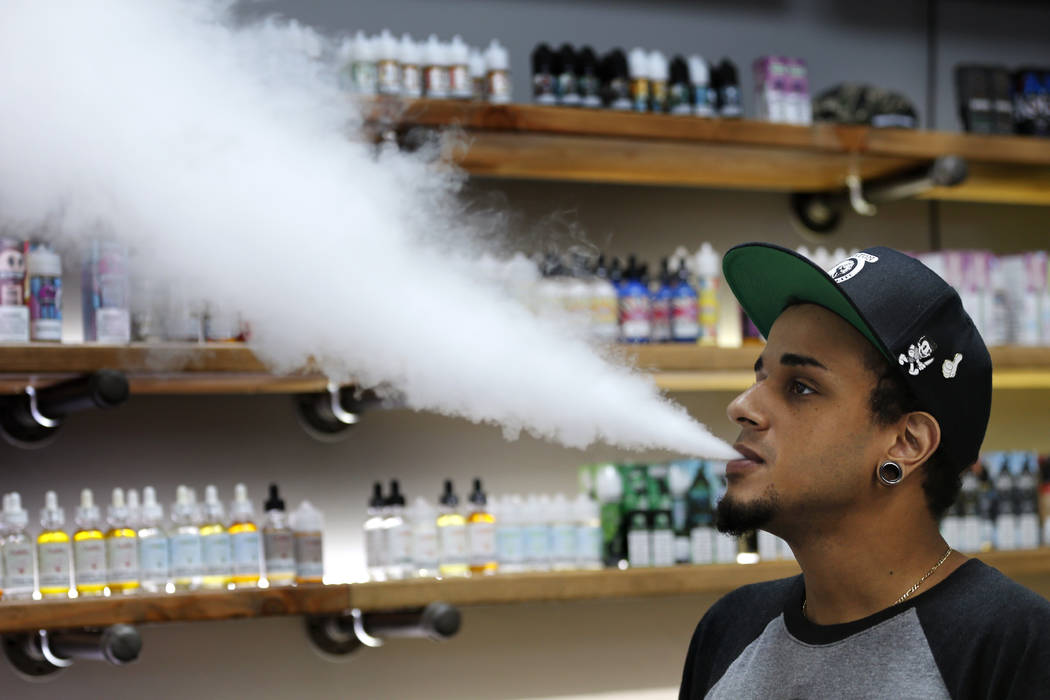 In this Tuesday, Sept. 3, 2019, photo, Andrew Teasley, a salesman at Good Guys Vape Shop, exhal ...
