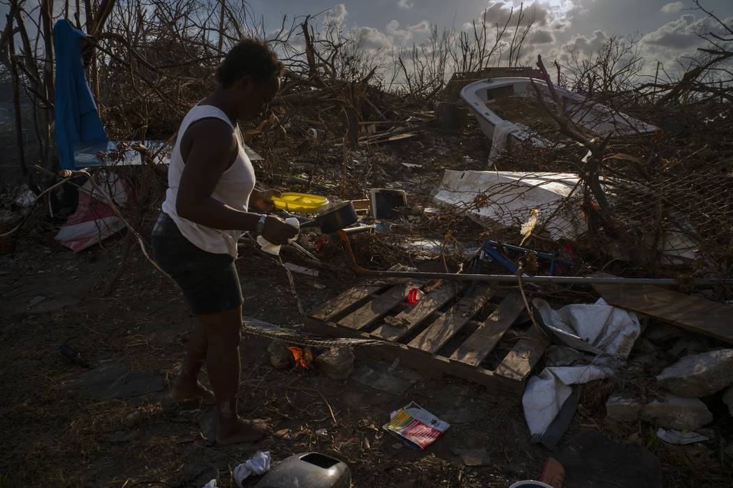 Tereha Davis, 45, holds a plate of rice as she walks among the remains of her shattered belongi ...