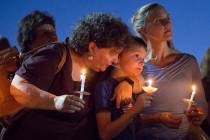 Paula Davis' brother Nathan Davis, center, holds a candle with his aunt Brenda Miraglia, left, ...