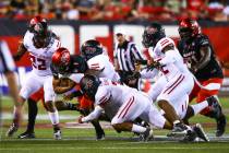 UNLV Rebels quarterback Armani Rogers (1) gets sacked by a phalanx of Arkansas State defenders, ...