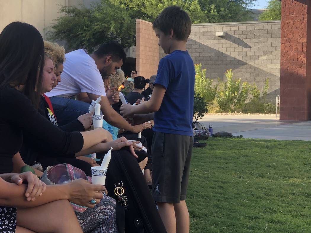 Nathan Davis helps light candles for those attending a vigil honoring his older sister at UNLV ...