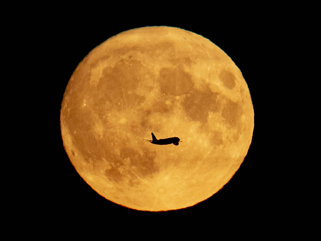 An aircraft passes the full moon as it approaches the airport in Frankfurt, Germany, Friday, Se ...