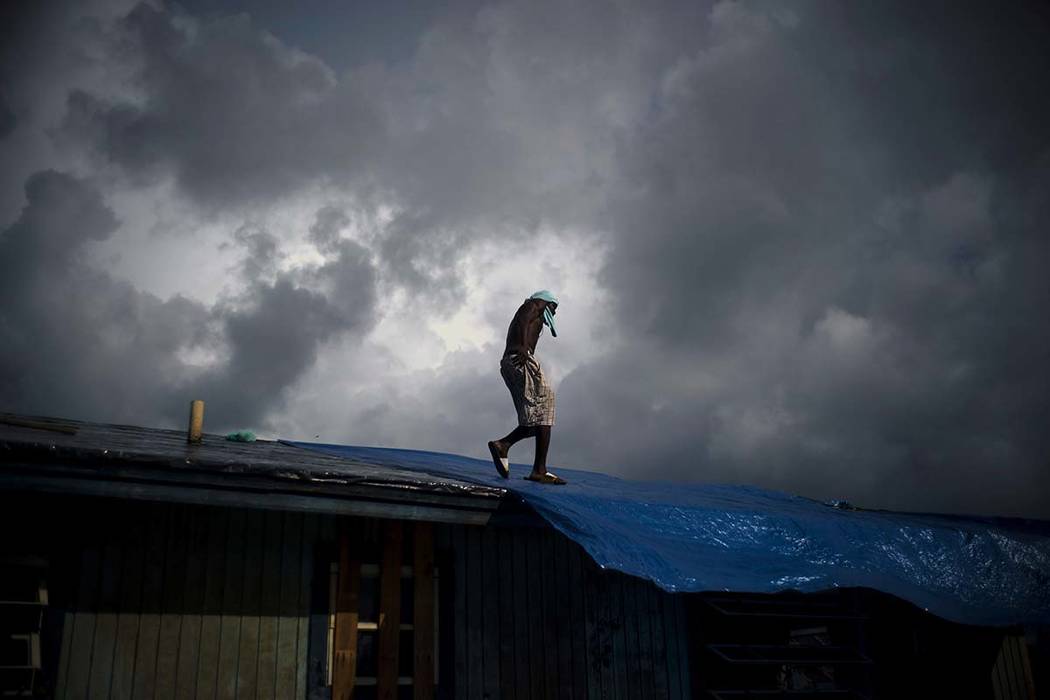 Trevon Laing walks the roof of his house to repair the damage made by Hurricane Dorian, in Gold ...