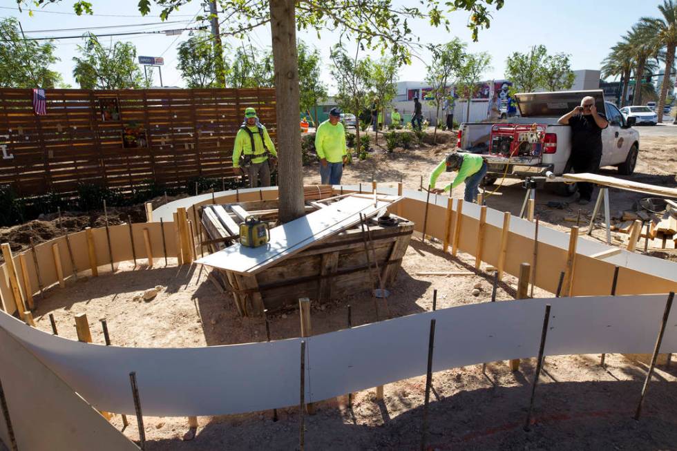 Landscapers work on a heart-shaped flower planter at an under-construction community healing ga ...