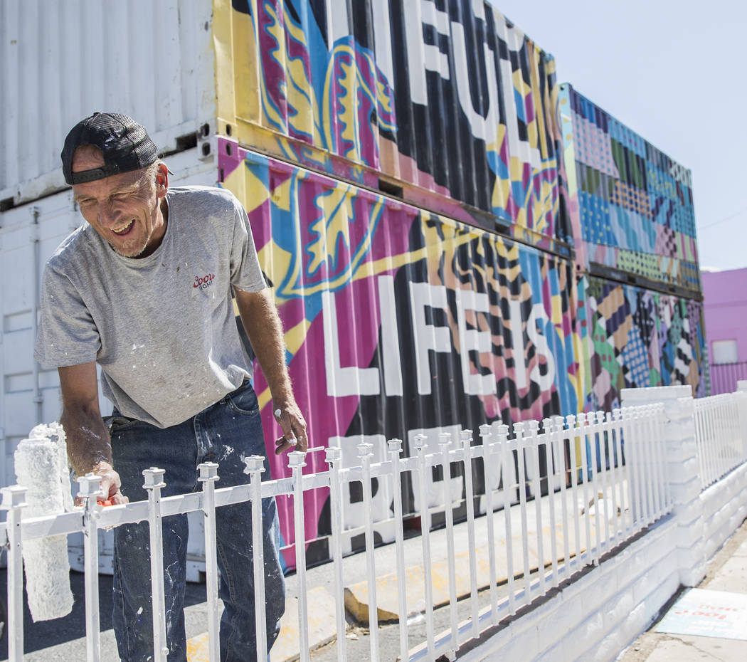 Jonathan Strublein paints a fence in preparation for Life is Beautiful music festival in downto ...
