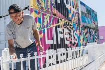 Jonathan Strublein paints a fence in preparation for Life is Beautiful music festival in downto ...