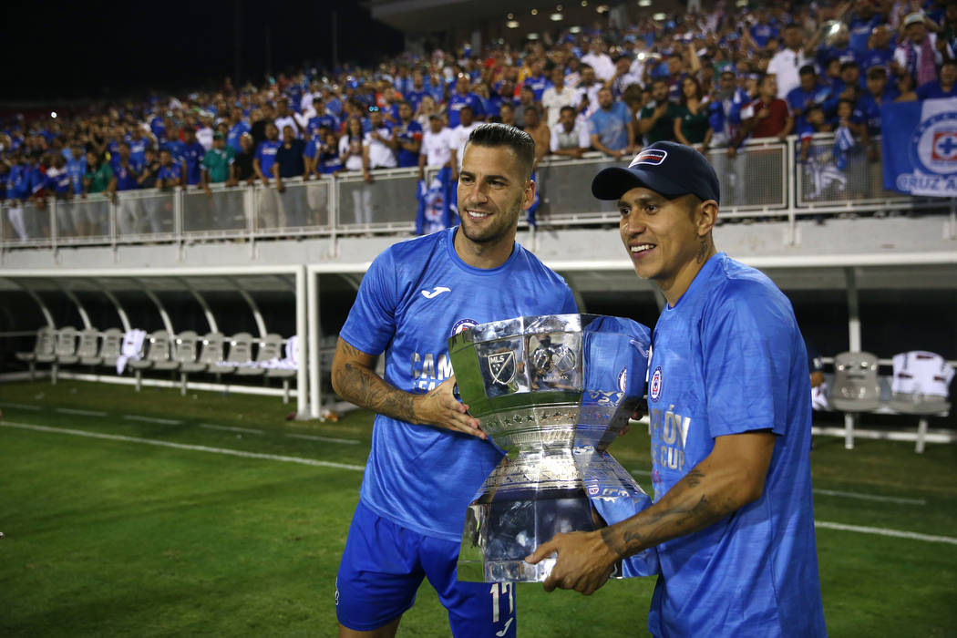Cruz Azul's Edgar Mendez (17), left, and Julio Dominguez (4), hold the trophy after their team ...
