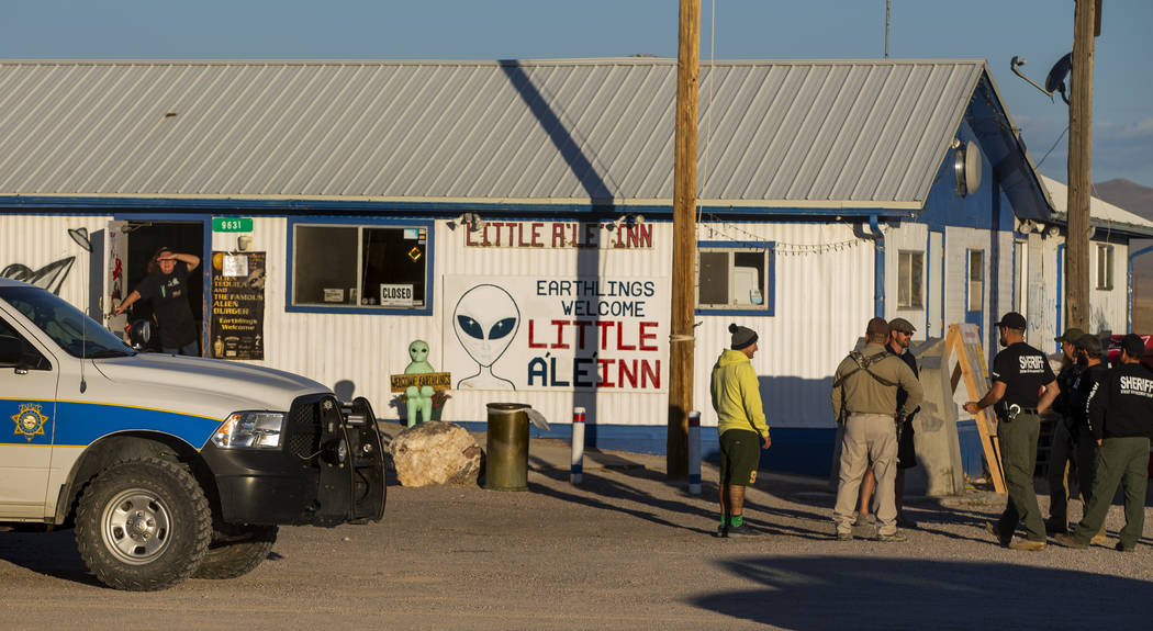Samantha Travis, left, peers out the door of the Little A'Le'Inn as law enforcement officers wa ...
