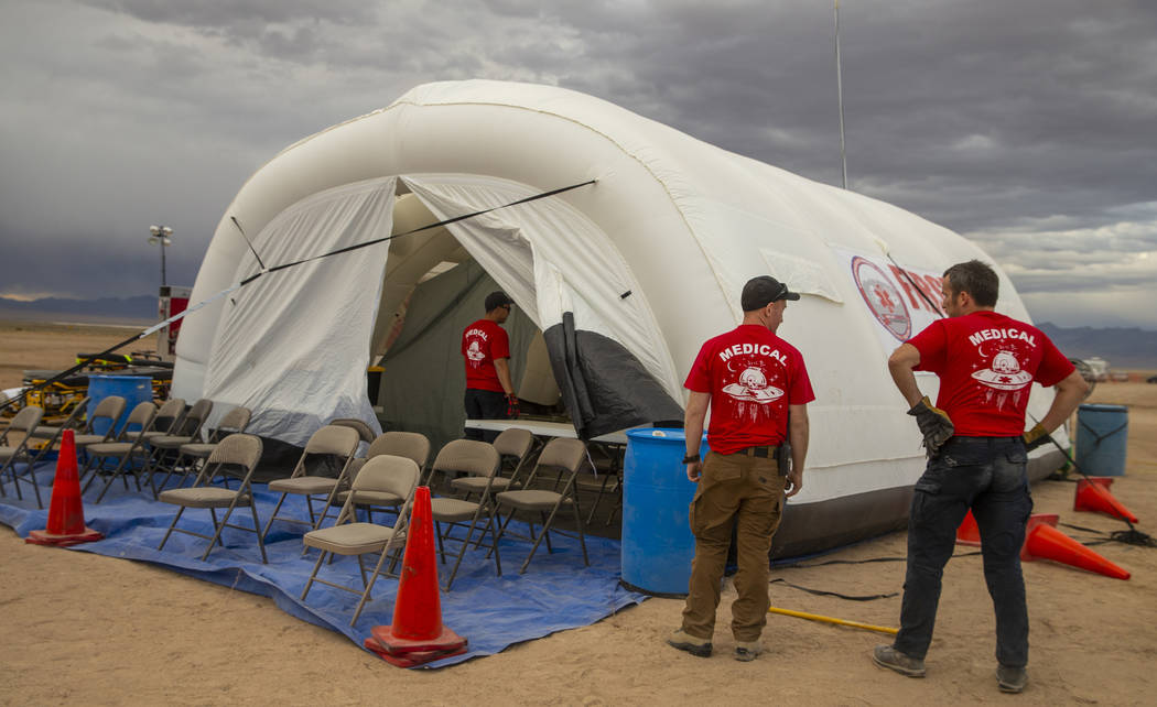The medical crew looks to tamp down their tent while winds pick up as the start of the Aliensto ...