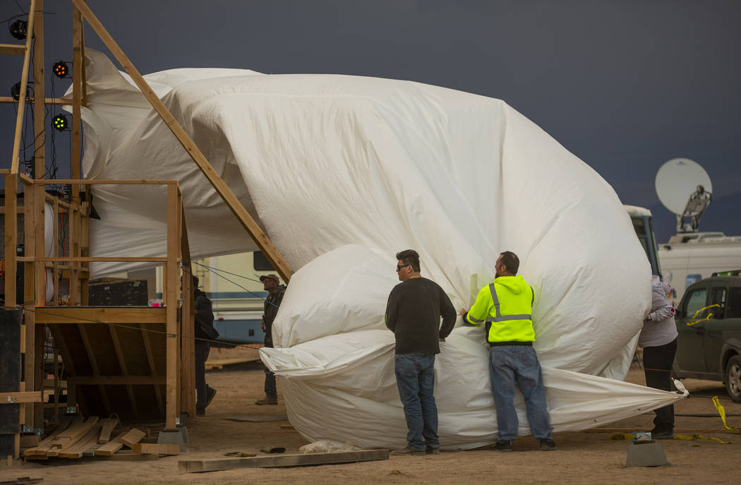 Volunteers help to secure the roof tarp on the main stage while it blows off from increasing wi ...