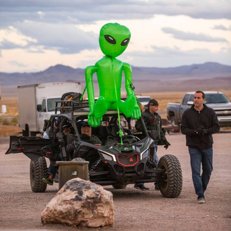 Festivalgoers arrive by all-terrain vehicle with an alien strapped to the top in front of the L ...