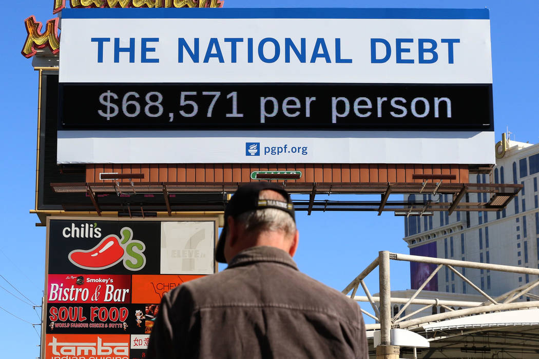 A pedestrian walks past a billboard depicting rising national debt on Las Vegas Boulevard direc ...
