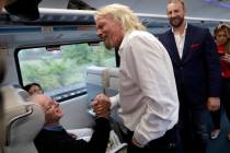 Richard Branson, of Virgin Group, center, greets a passenger while riding a Brightline train fr ...