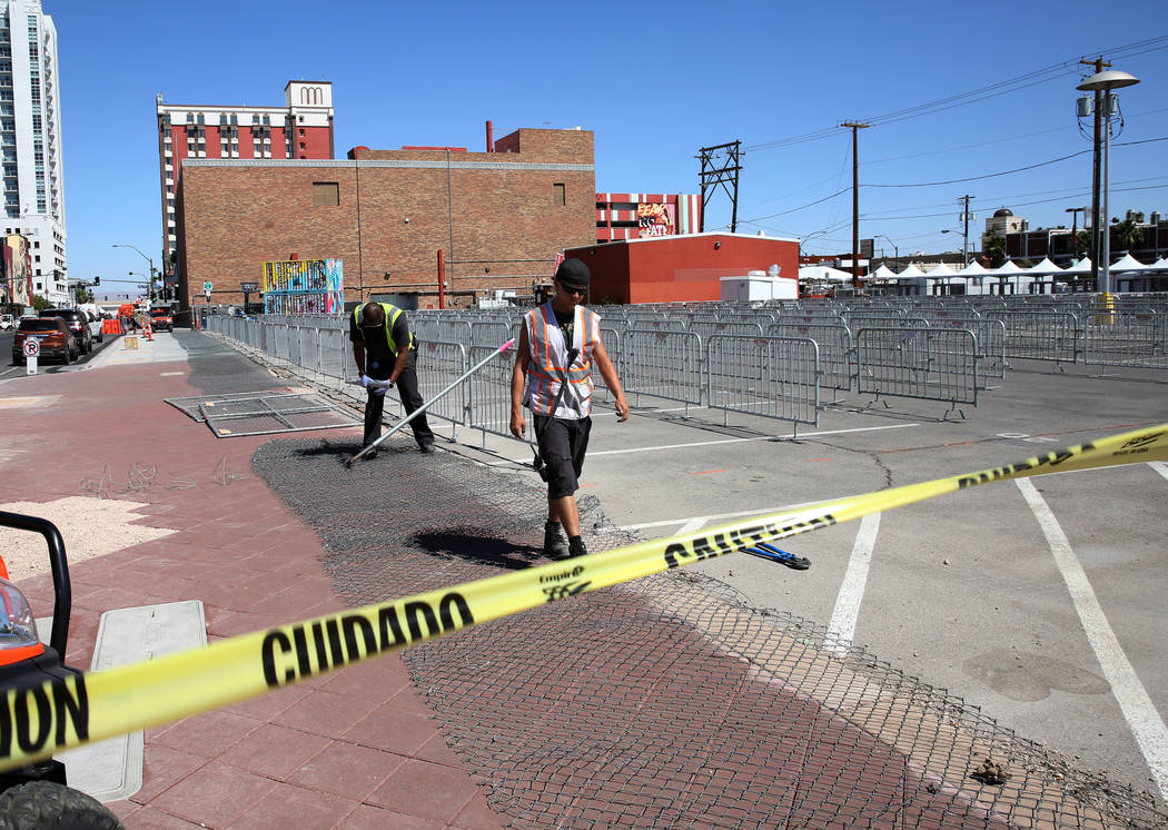 Workers put up temporary fences at the corner of Carson Avenue and Seventh Street in preparatio ...