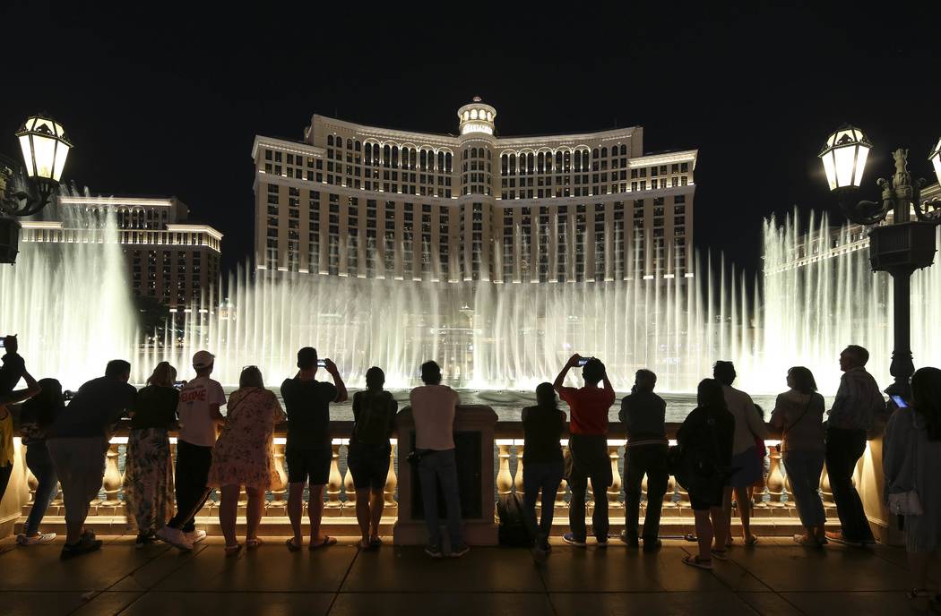 People watch the water fountain show outside the Bellagio hotel and casino on the Strip in Las ...