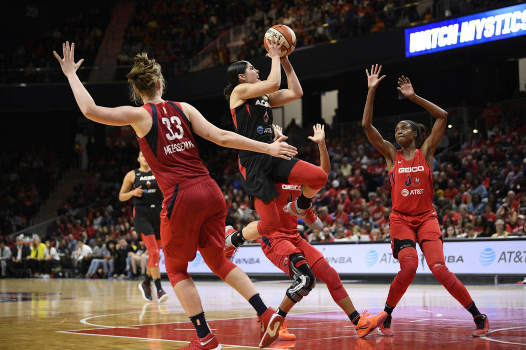 Las Vegas Aces guard Kelsey Plum, center, goes to the basket against Washington Mystics center ...