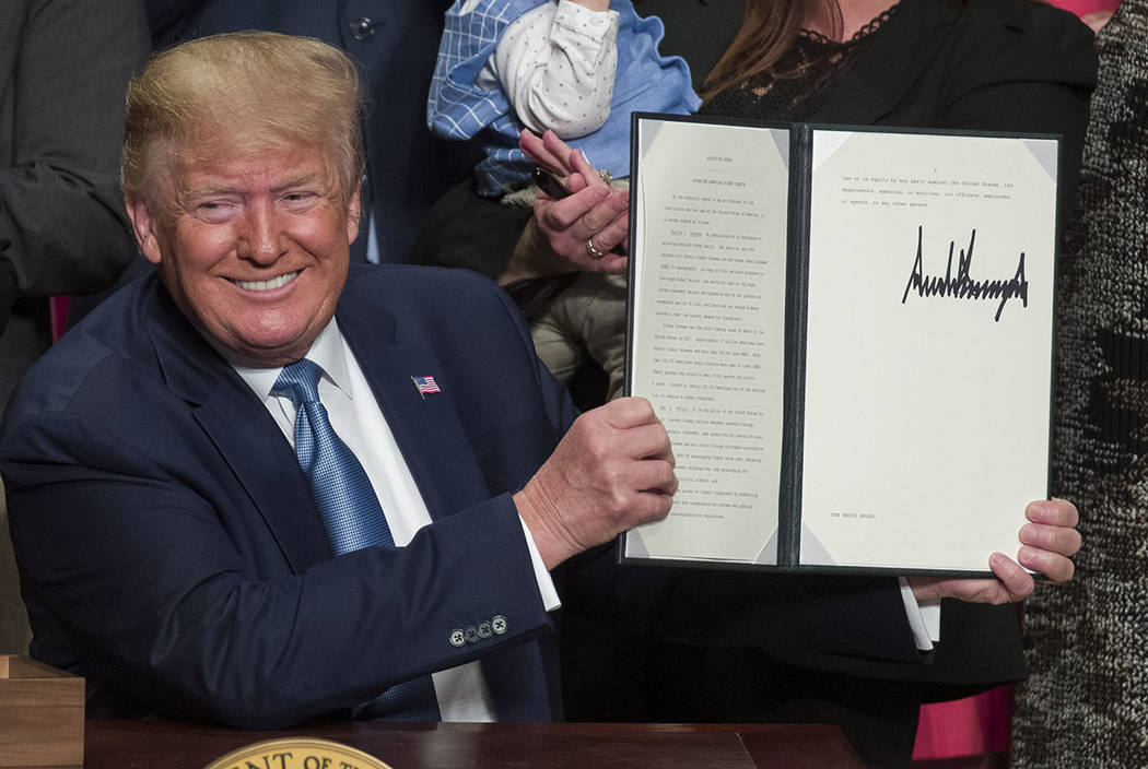 President Donald Trump holds up a signed executive order at the Ronald Reagan Building and Inte ...