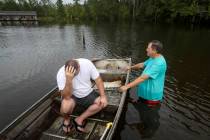 Stephen Gilbert, left, and his father-in-law sit in front of their flooded property on Friday, ...