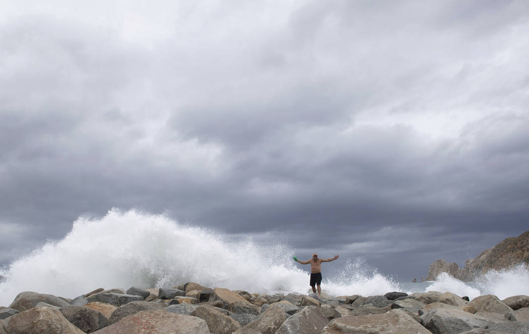 A tourist poses for a photo in front breaking waves before the expected arrival of Hurricane Lo ...