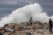 A tourist poses for a photo in front breaking waves before the expected arrival of Hurricane Lo ...