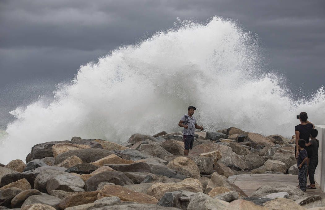 A tourist poses for a photo in front breaking waves before the expected arrival of Hurricane Lo ...