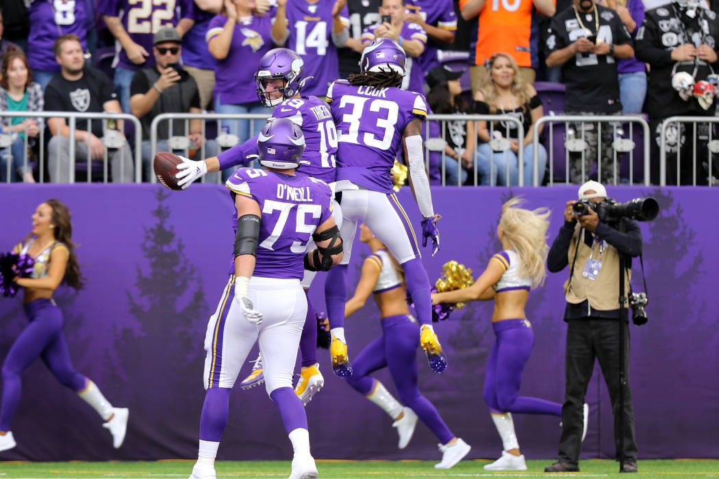 Minnesota Vikings wide receiver Adam Thielen (19) jumps in the air with running back Dalvin Coo ...